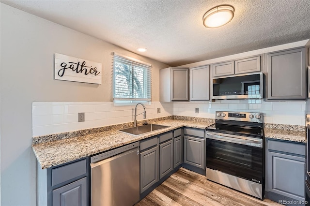 kitchen with tasteful backsplash, gray cabinetry, sink, and appliances with stainless steel finishes