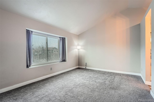 carpeted spare room with vaulted ceiling