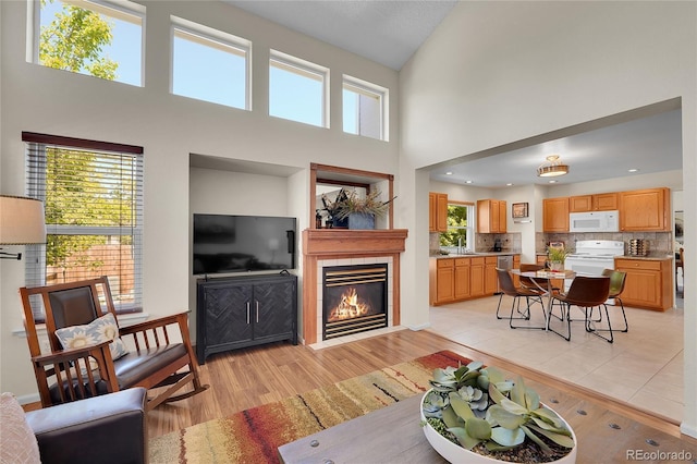 19075 E Grand Cir, Aurora, CO 80015 - living room featuring a tiled fireplace, high vaulted ceiling, and light wood-style flooring