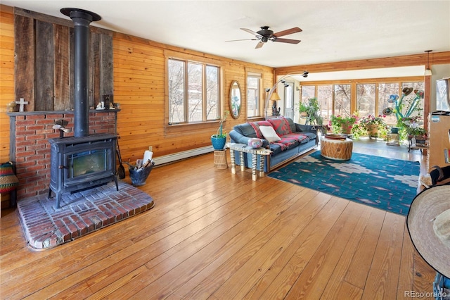 400 W Galena, Moffat, CO 81131 - living area with a wood stove, ceiling fan, hardwood / wood-style floors, baseboard heating, and wood walls