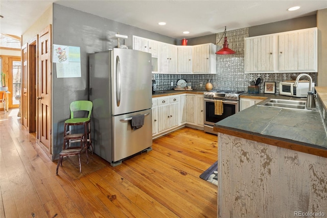 400 W Galena, Moffat, CO 81131 - kitchen featuring appliances with stainless steel finishes, light wood-style flooring, tasteful backsplash, dark countertops, and recessed lighting