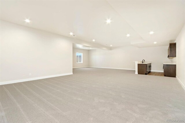 1889 Spring Bloom Dr, Windsor, CO 80550 - unfurnished living room with bar with sink, recessed lighting, light colored carpet, and baseboards