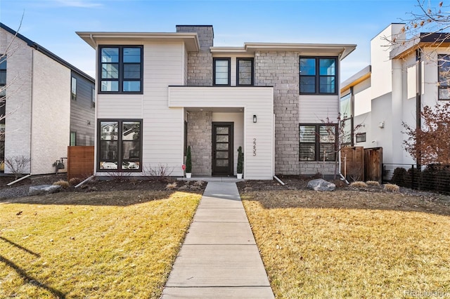 view of front of home with stone siding and a front lawn