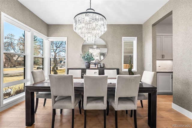 dining room featuring baseboards, a notable chandelier, and light wood finished floors