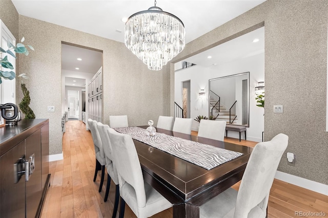 dining area featuring a chandelier, baseboards, stairs, light wood-type flooring, and wallpapered walls