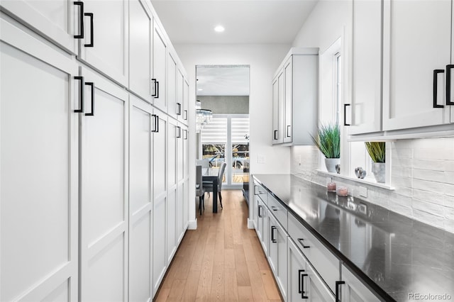 kitchen featuring recessed lighting, white cabinets, decorative backsplash, dark stone counters, and light wood finished floors