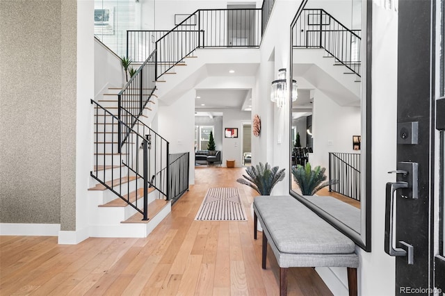 foyer featuring wood-type flooring, a high ceiling, baseboards, and stairs