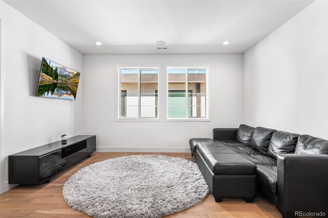 living room featuring recessed lighting, baseboards, visible vents, and light wood finished floors