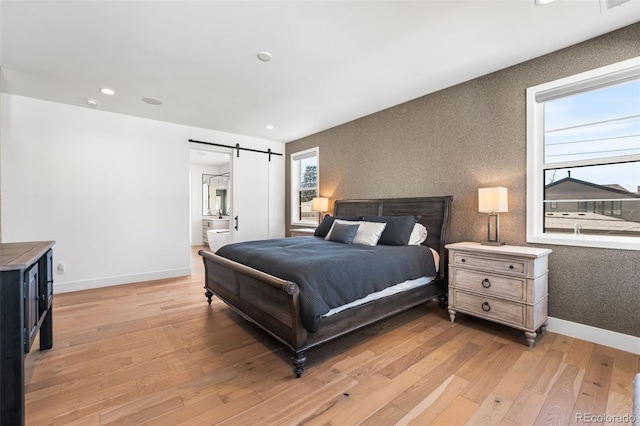 bedroom with wallpapered walls, a barn door, baseboards, light wood-style floors, and recessed lighting