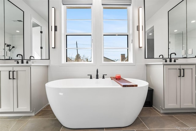 bathroom with a sink, a soaking tub, tile walls, and two vanities