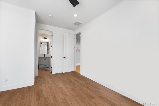 unfurnished bedroom featuring baseboards, visible vents, wood finished floors, and ensuite bathroom