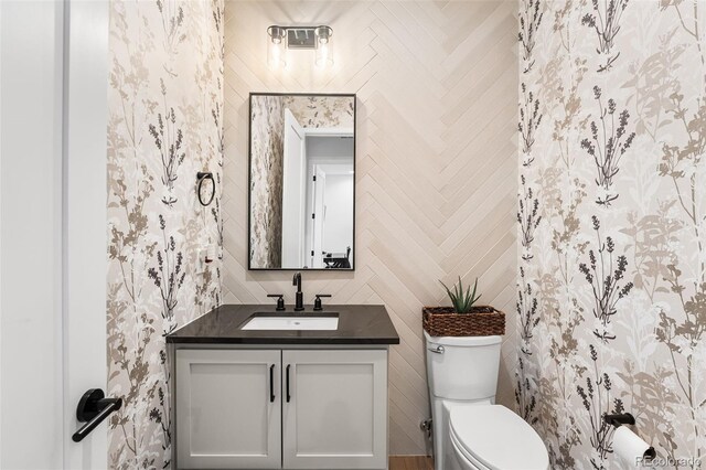 half bath with toilet, tile walls, and vanity