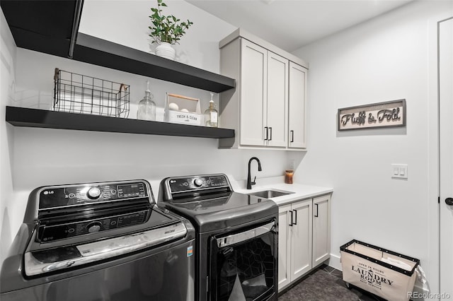 laundry room featuring dark tile patterned floors, a sink, cabinet space, and washer and dryer