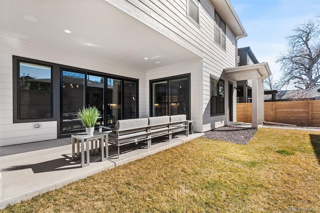 back of house with fence, an outdoor living space, a patio, and a yard