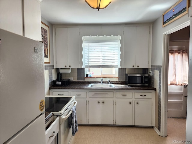 kitchen featuring white electric range, white cabinetry, fridge, and sink