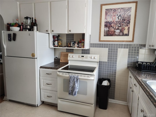 kitchen with white cabinets, dark stone counters, white appliances, and light tile patterned floors