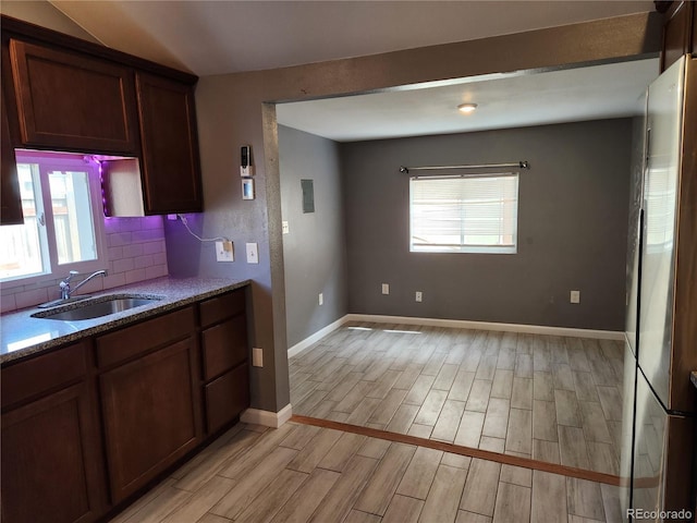 kitchen featuring sink, light stone counters, tasteful backsplash, and a healthy amount of sunlight