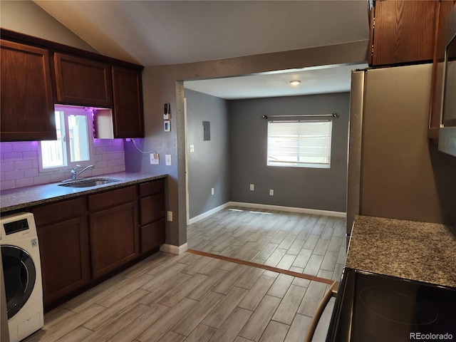 kitchen with washer / dryer, range with electric cooktop, decorative backsplash, sink, and vaulted ceiling