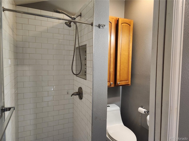 bathroom featuring toilet and a tile shower