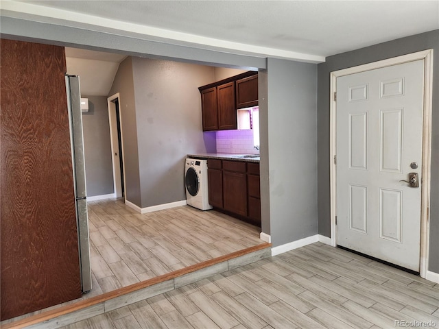 kitchen featuring sink, washer / clothes dryer, tasteful backsplash, light hardwood / wood-style floors, and dark brown cabinetry