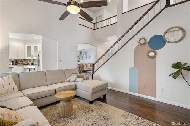2249 Weatherstone Cir, Highlands Ranch, CO 80126 - living room with arched walkways, dark wood finished floors, a high ceiling, a ceiling fan, and stairs