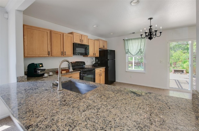 7871 Ogden Ct, Denver, CO 80229 - kitchen with black appliances, light stone countertops, a chandelier, tile patterned flooring, and a peninsula