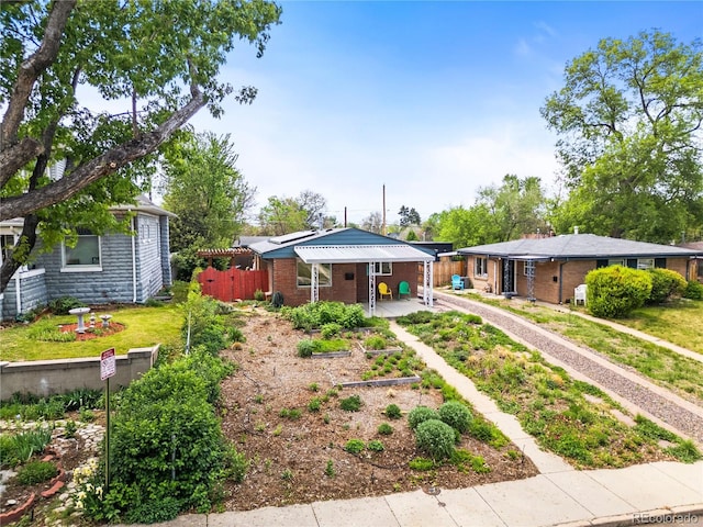 view of front of home featuring driveway, fence, and brick siding