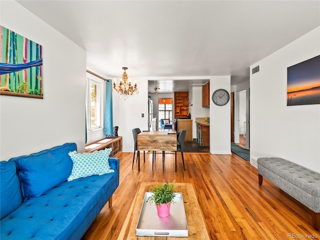 living area featuring a chandelier, wood finished floors, and baseboards
