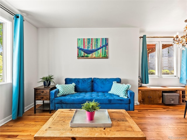 living room featuring light wood finished floors, a chandelier, and baseboards
