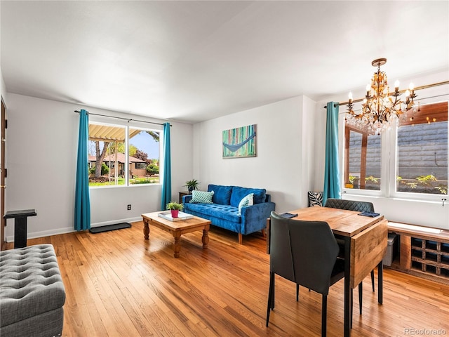 living room with a chandelier, light wood finished floors, and baseboards