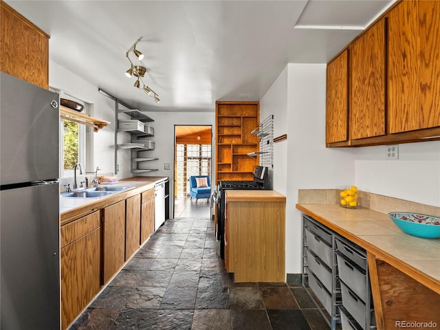 kitchen with stainless steel appliances, open shelves, a sink, stone tile floors, and brown cabinets
