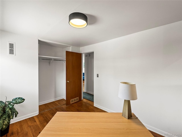 unfurnished bedroom with wood finished floors, baseboards, and a closet