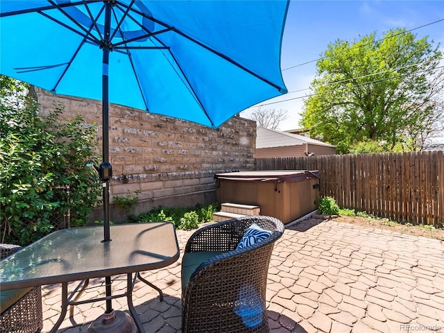 view of patio with a hot tub, outdoor dining area, and a fenced backyard
