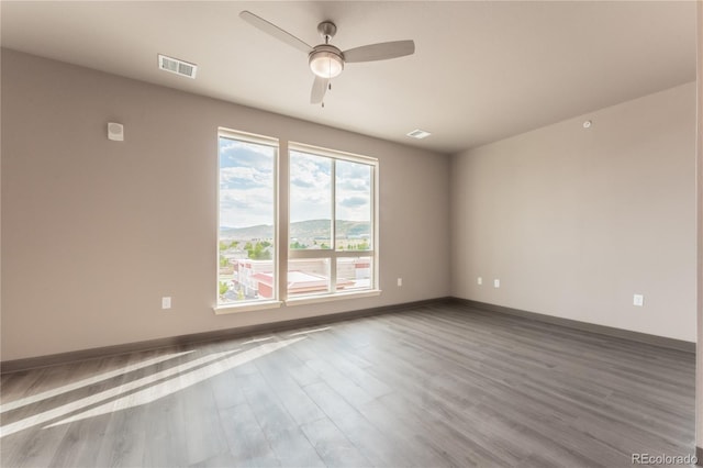 empty room featuring hardwood / wood-style floors, a mountain view, and ceiling fan