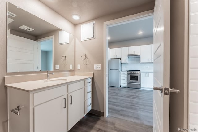 12983 W Ida Ave Unit 104, Littleton, CO 80127 - bathroom featuring wood finished floors, visible vents, baseboards, tasteful backsplash, and vanity