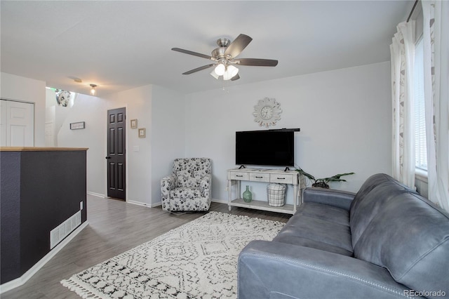 living room with wood finished floors, baseboards, and ceiling fan