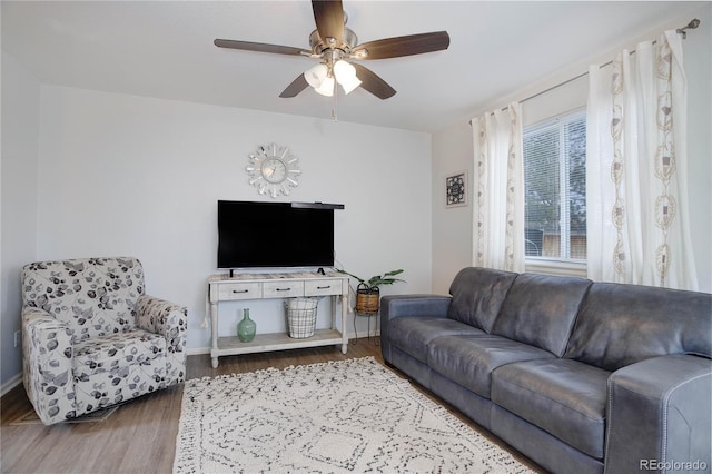 living room featuring baseboards, a ceiling fan, and wood finished floors