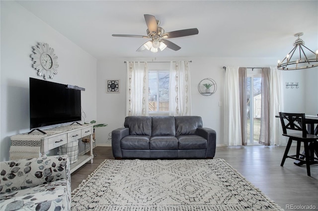 living room with baseboards, wood finished floors, and ceiling fan with notable chandelier