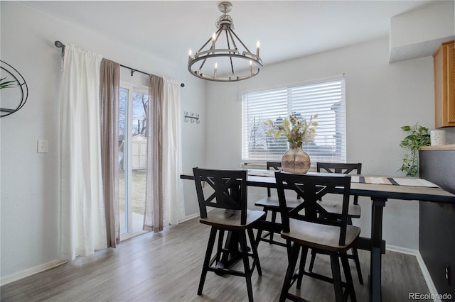 dining area featuring light wood-type flooring, plenty of natural light, a notable chandelier, and baseboards