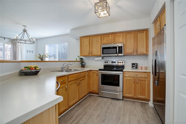 kitchen featuring a healthy amount of sunlight, appliances with stainless steel finishes, light wood-style floors, and a sink