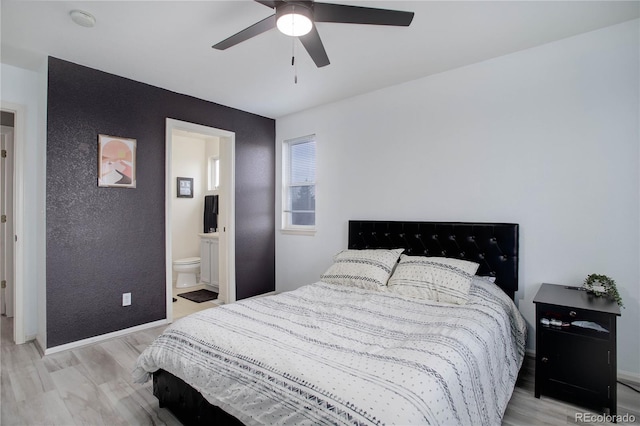 bedroom featuring connected bathroom, baseboards, light wood-style floors, and a ceiling fan