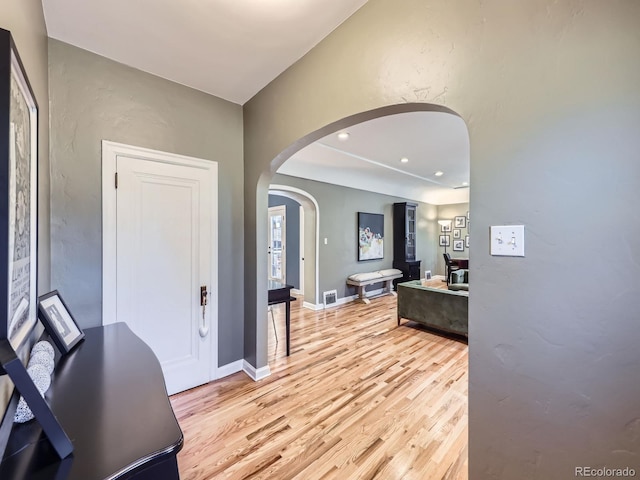 entryway with arched walkways, recessed lighting, light wood-type flooring, and baseboards