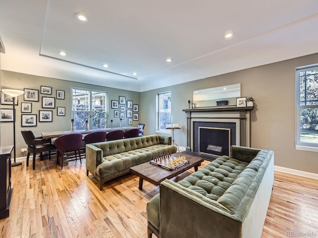 living area with light wood finished floors, recessed lighting, a fireplace, and baseboards