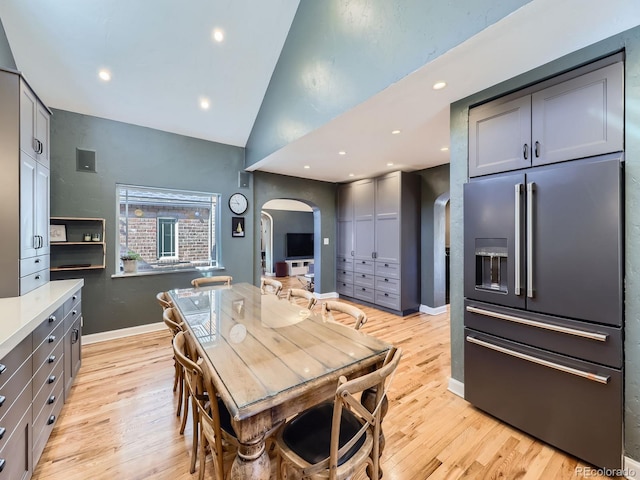 kitchen featuring gray cabinetry, vaulted ceiling, light wood-style floors, arched walkways, and high end fridge