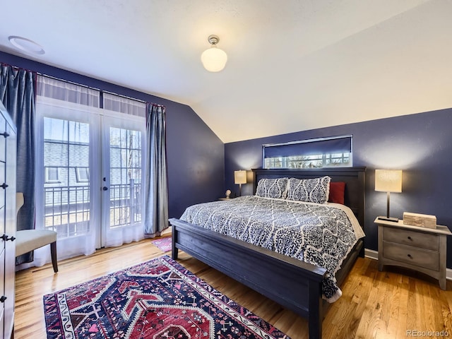 bedroom with access to outside, vaulted ceiling, baseboards, and wood finished floors