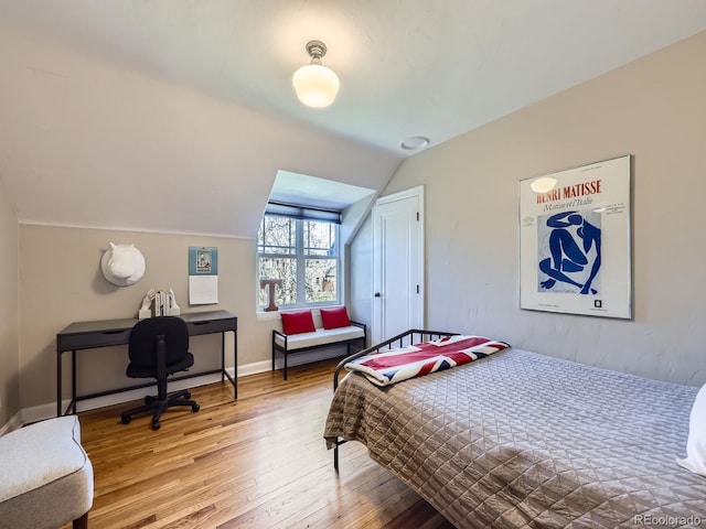 bedroom featuring vaulted ceiling, baseboards, and wood-type flooring