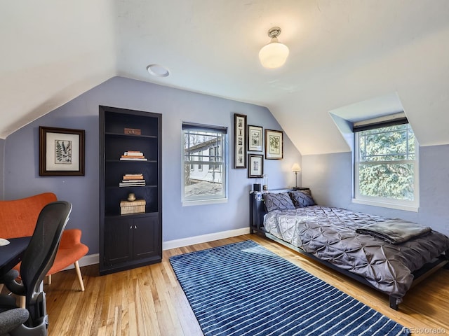 bedroom featuring vaulted ceiling, multiple windows, and light wood-type flooring