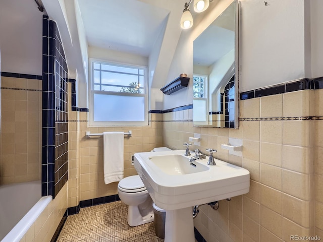 full bath featuring tile patterned flooring, a wainscoted wall, toilet, and tile walls