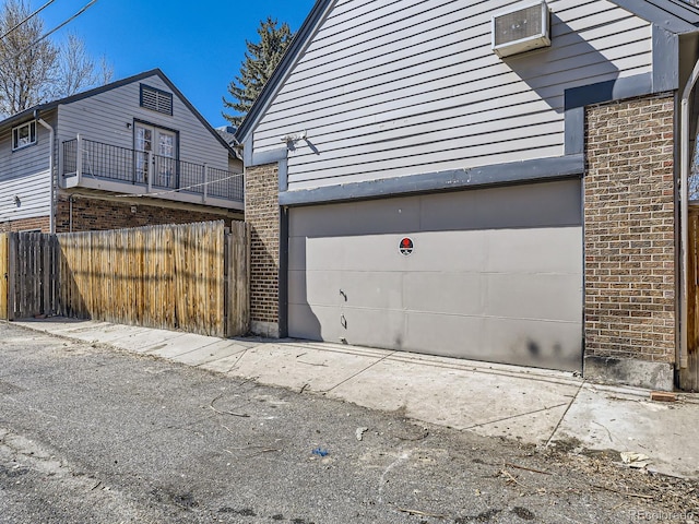 garage featuring a wall unit AC and fence