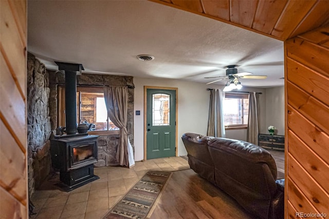 entryway with ceiling fan and a wood stove